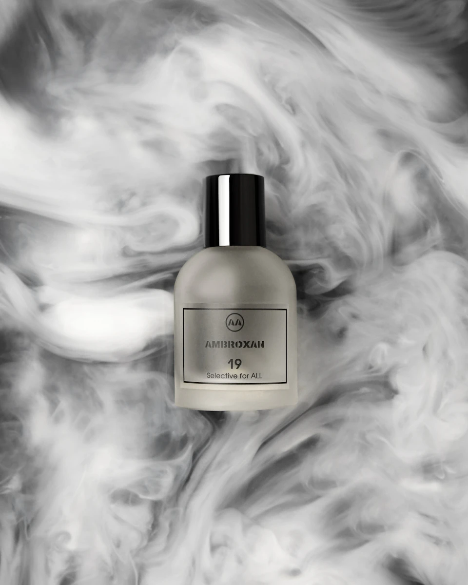 Fotografia de produto: frasco de perfume cercado por formas de fumaça.